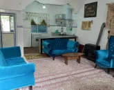 اتاق پذیرایی فرش شده و مبلمان آبی با بخاری گازی و آشپزخانه با یخچال، لباسشویی خانه ویلایی در قشم 56488